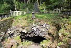 岩の間の小さな洞穴の前に石段と灯籠がある祠